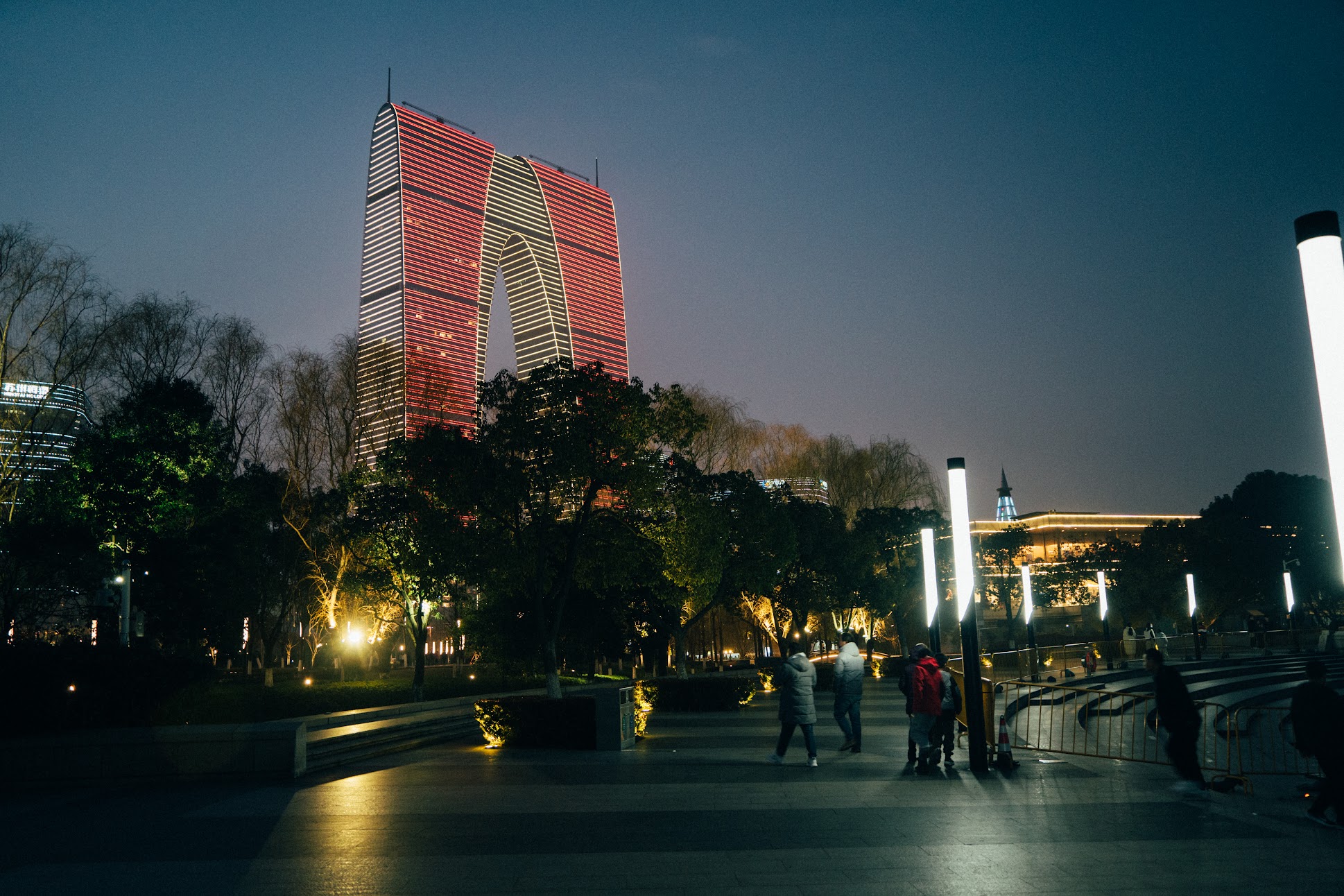 Gate of the Orient outlined in red lights above a park walkway at night